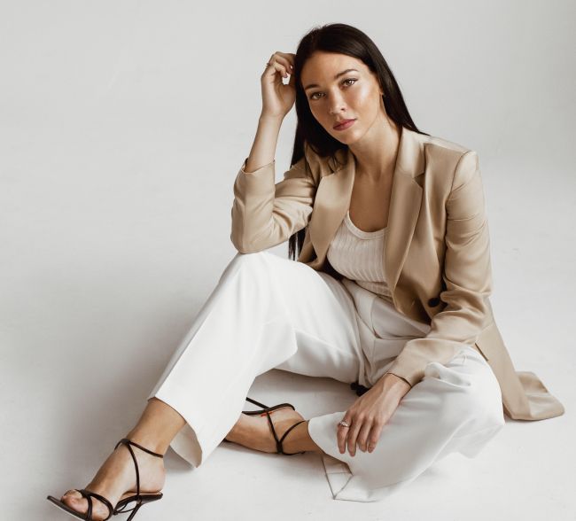Woman in stylish outfit, seated on floor.