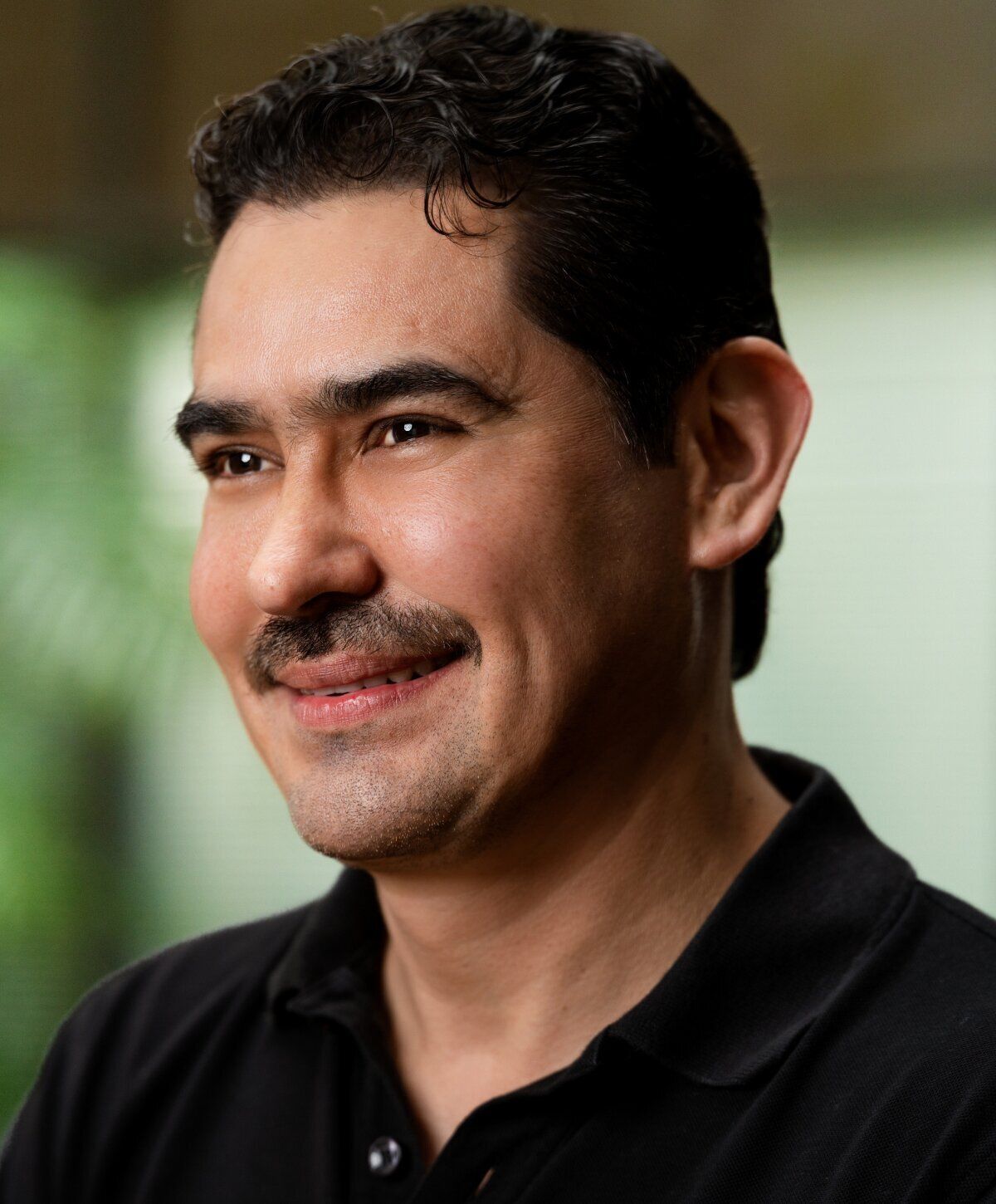 Smiling man in black polo shirt.