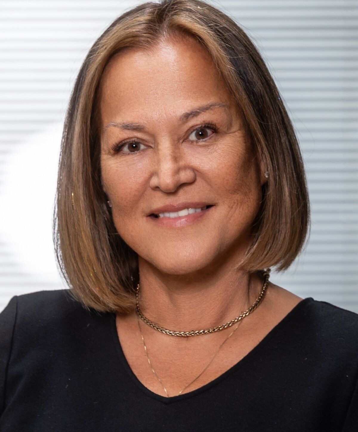 Smiling woman with medium-length hair and necklace.