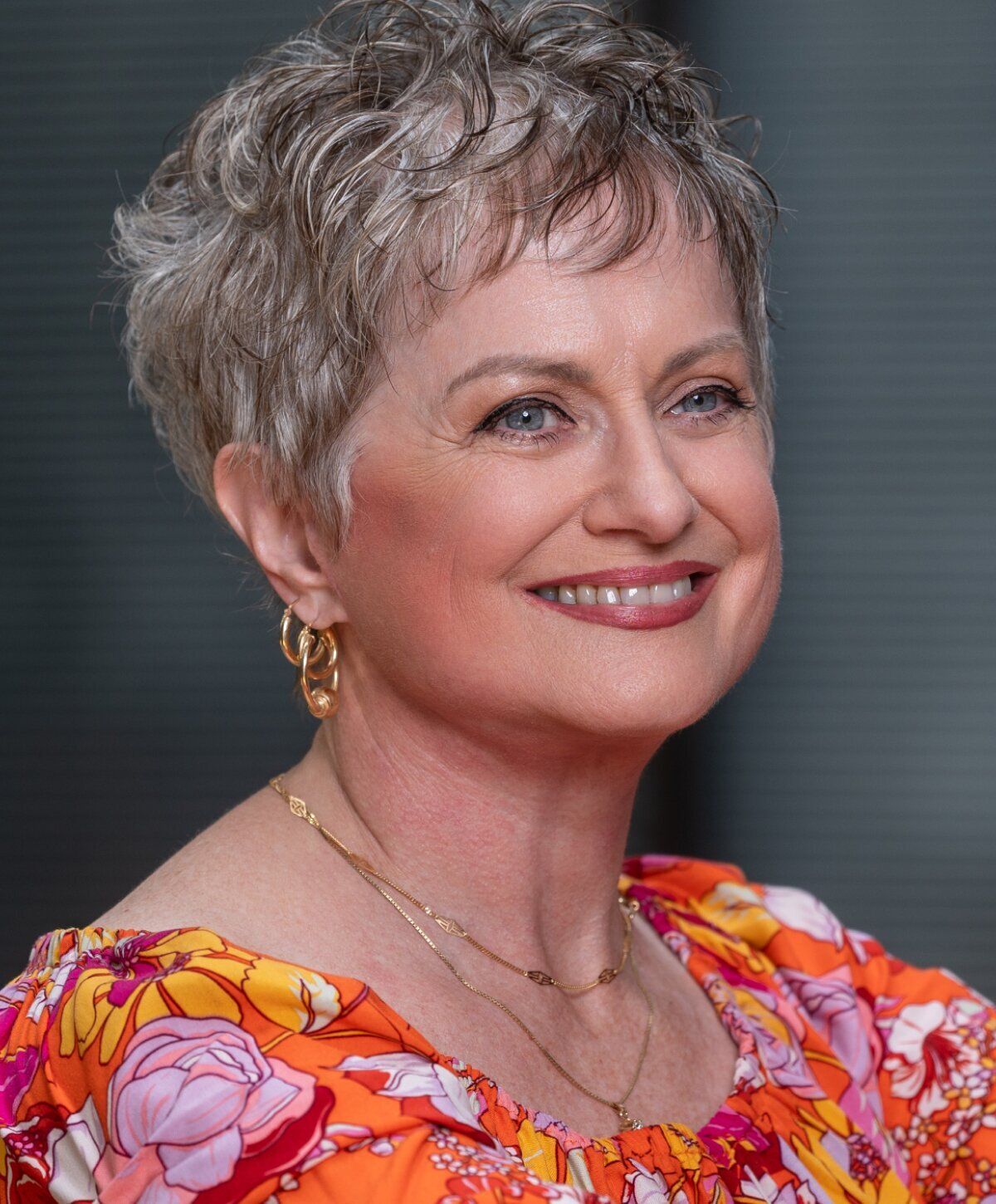 Smiling woman in colorful floral blouse.