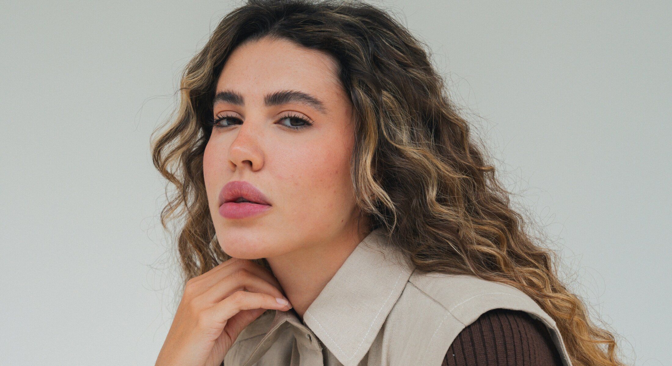 Woman with curly hair and thoughtful expression.