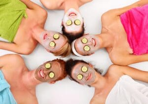A picture of five girl friends relaxing with facial masks on over white background