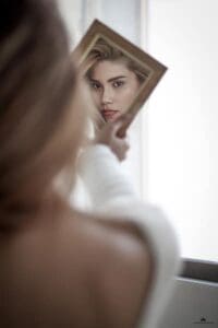 blonde woman looking into the mirror