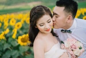 asian bride and groom, groom kissing brides cheek, sunflowers in background