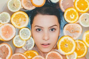 womans face surrounded by oranges