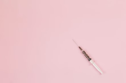injectable needle against baby pink background