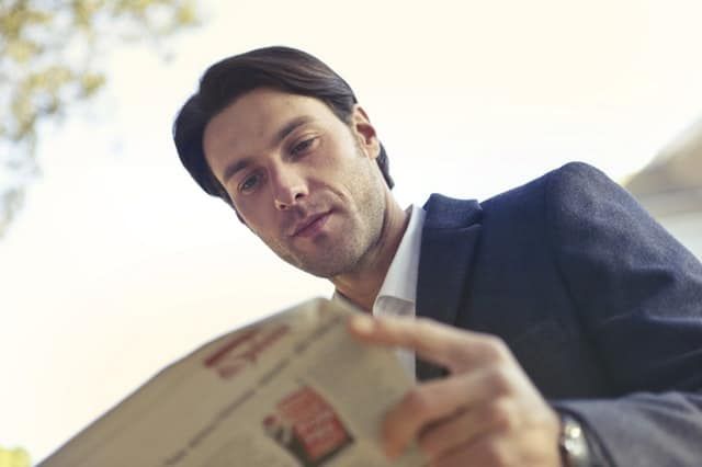 man in suit reading the newspaper
